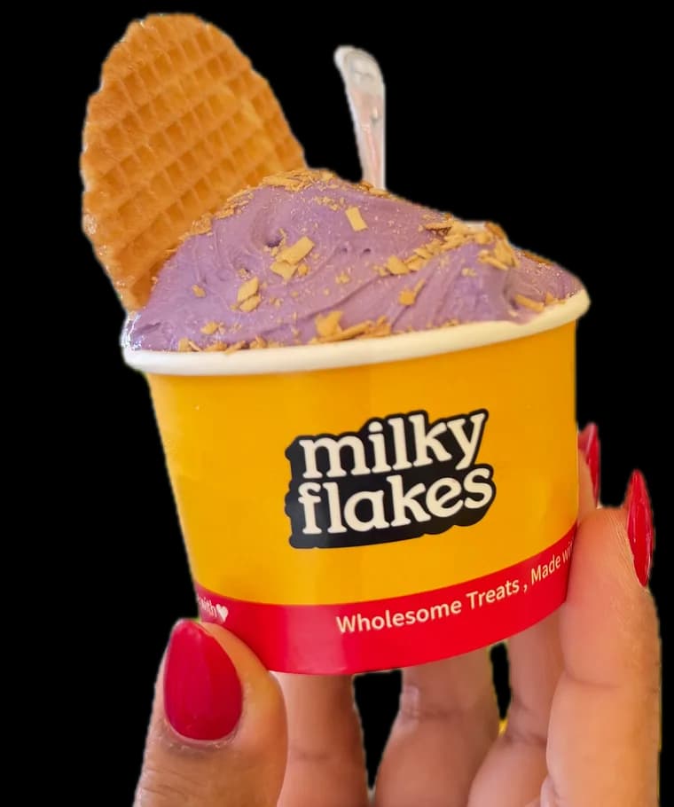 A cup of ube soft scoops with a waffle, held up in a hand.