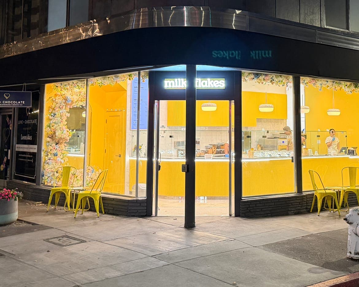 The shop at night on its corner in downtown Walnut Creek, the yellow room lit behind the glass.